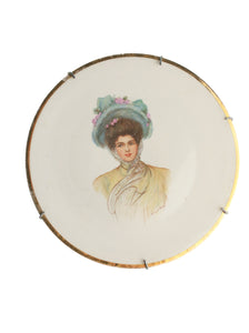 Decorative plate with a portrait of a woman in a pastel dress and hat on a white background