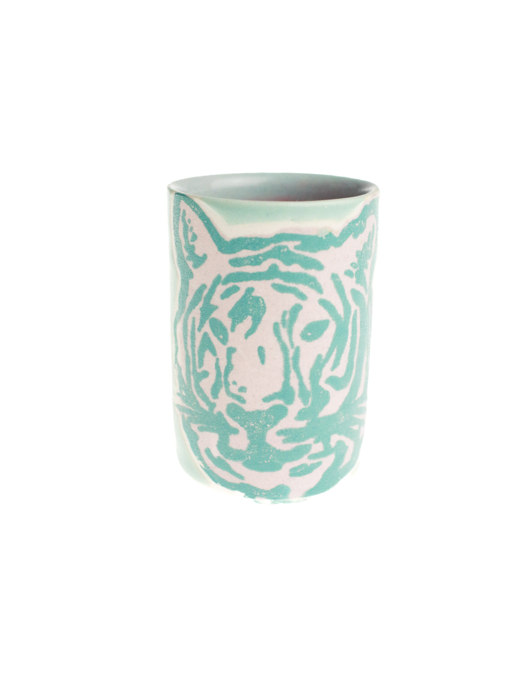 A ceramic shot glass with a tiger design and a pastel green color.
