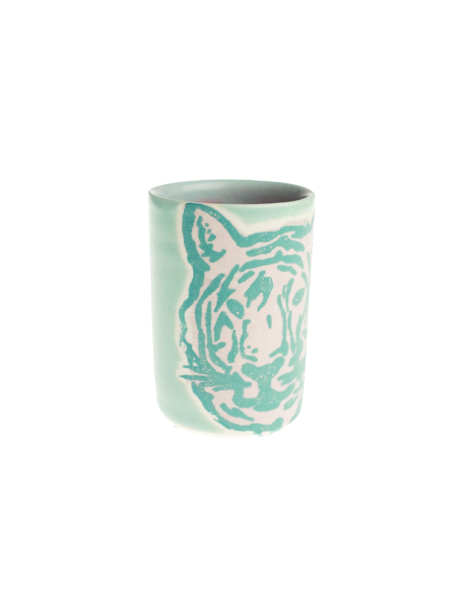A ceramic shot glass with a tiger design and a pastel green color.