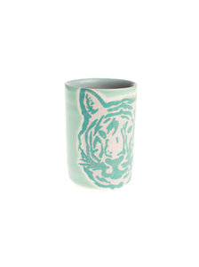 A ceramic shot glass with a tiger design and a pastel green color.