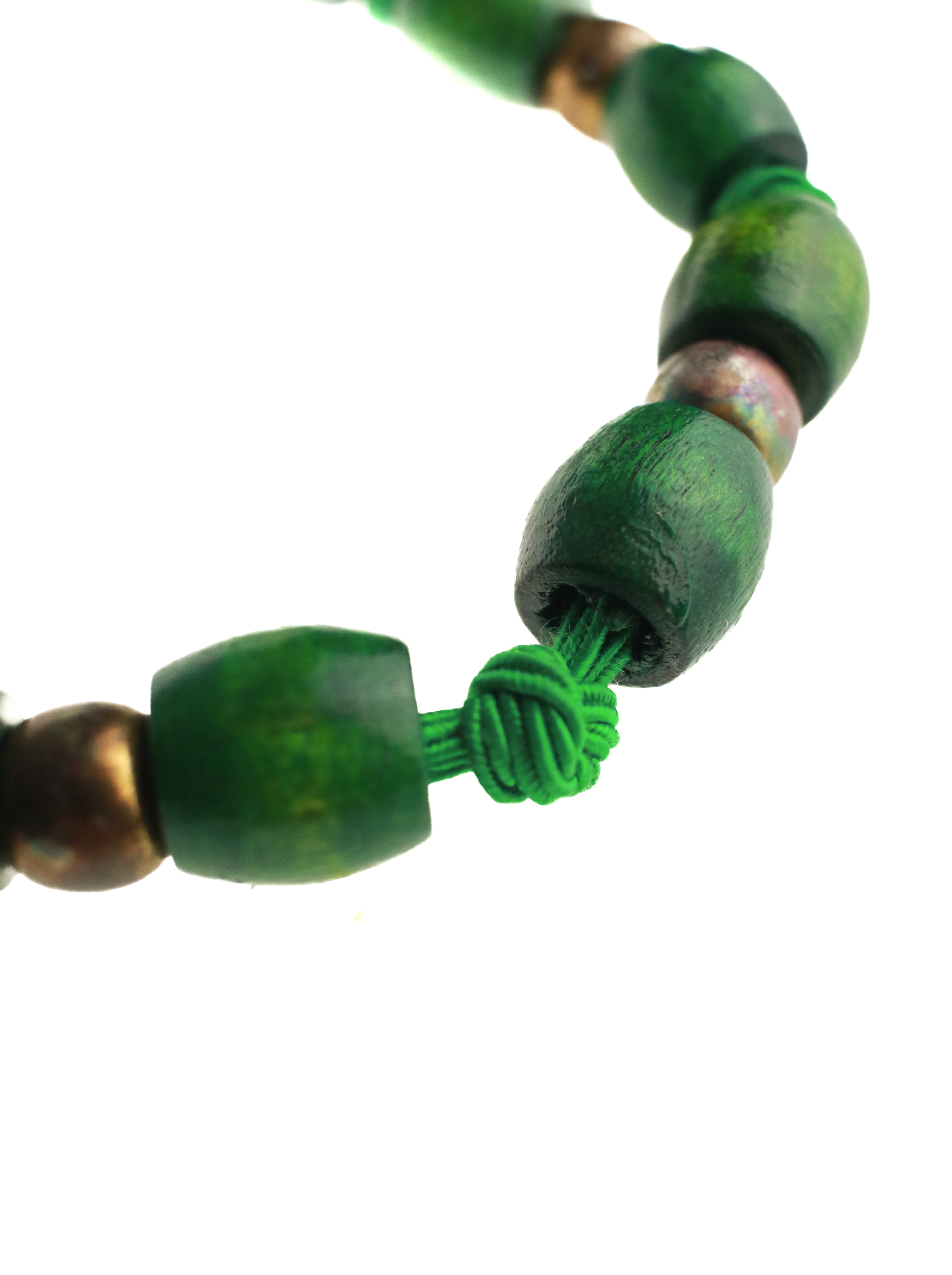 Close-up of a green and brown beaded necklace on a white background