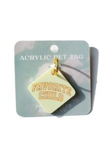 yellow acrylic dog tag with orange lettering on blue paper holder and white background