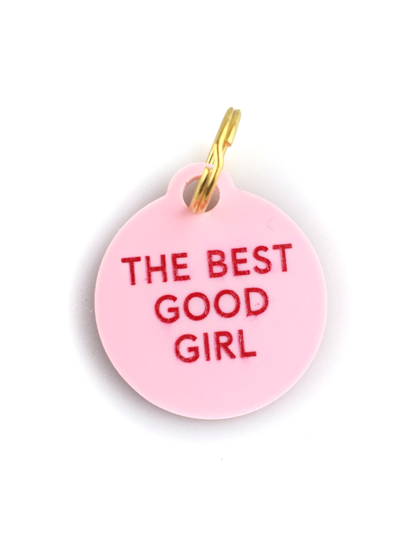 pink acrylic dog tag with red lettering and gold ring on white background